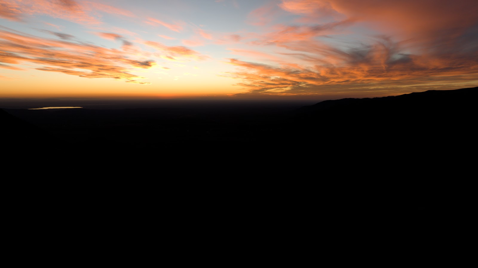 The sierras at dusk from the air, an orange sky above dark hills